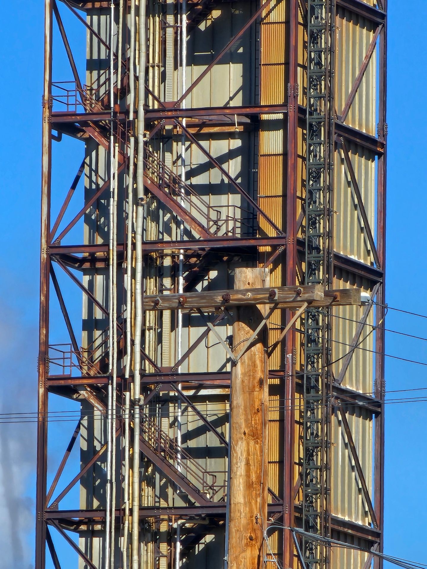 Industrial scaffolding structure with metal beams and pipes against a clear blue sky.